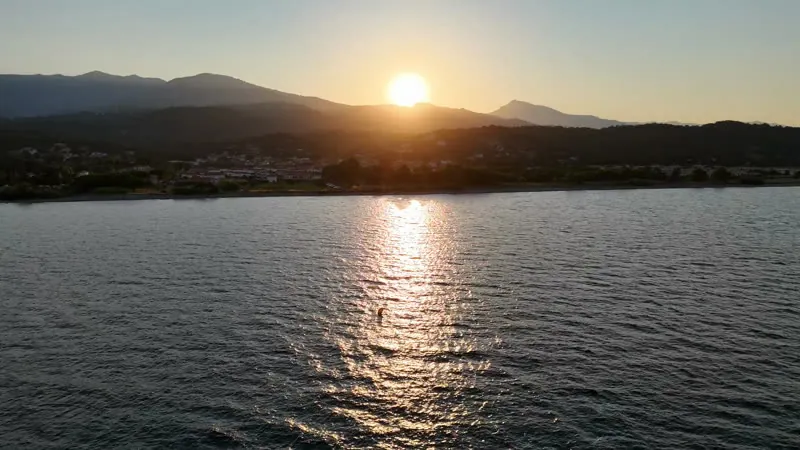 Le soleil se couche derrière la montagne, reflet sur l’eau