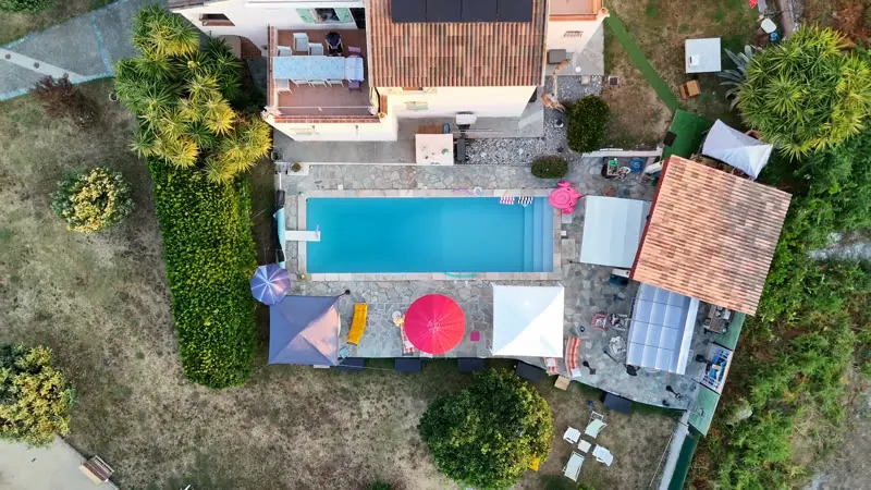 La piscine vue du ciel, entourée de transats et de parasols