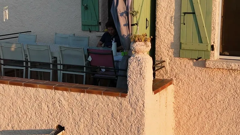 La grande table sur la terrasse, à l’ombre, volets verts ouverts